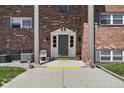 Close up of a brick condominium building featuring a front door with a small porch and American flags at 5038 Allisonville Rd # E, Indianapolis, IN 46205