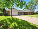 View of the home with attached garage, basketball hoop, and manicured lawn and driveway at 5200 N Leslie Dr, Muncie, IN 47304