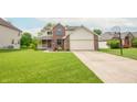 Well-maintained home with a lush green lawn, brick accents, vinyl siding, and a two-car garage at 6039 Chinkapin Dr, Columbus, IN 47201