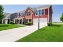 Charming two-story home with red siding, brick accents, long driveway, and attached two car garage at 6212 N Woods Edge Dr, McCordsville, IN 46055
