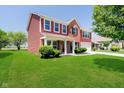 Charming two-story home with red siding, brick accents, manicured lawn, and covered front porch at 6212 N Woods Edge Dr, McCordsville, IN 46055