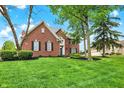 Charming brick home featuring a well-manicured lawn and mature trees at 7248 River Birch Ln, Indianapolis, IN 46236