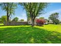 Lush green yard with mature trees and a privacy fence defines this property's ample outdoor space at 813 Stoner Dr, Anderson, IN 46013