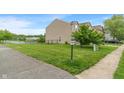 Well-maintained side yard with lush green grass, sidewalk, and partial water view at 8238 Crackling Ln, Indianapolis, IN 46259