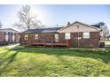 Back exterior of brick home with a spacious wooden deck and a well maintained lawn at 8510 E Mcgregor Rd, Indianapolis, IN 46259