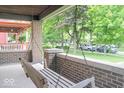 Relaxing front porch featuring a classic porch swing and brick columns at 989 Woodruff Pl E Dr, Indianapolis, IN 46201