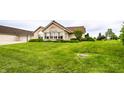 Well-manicured lawn surrounds brick home with large windows and an attached garage at 11646 Winding Wood Dr, Indianapolis, IN 46235