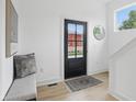 Inviting foyer featuring a black front door, bench seat, hardwood floors, and a decorative mirror at 1231 Marlowe Ave, Indianapolis, IN 46202