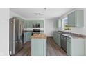Bright kitchen with sage cabinets, stainless steel appliances, an island, and wood-look flooring, creating a cozy feel at 12422 River Valley Dr, Fishers, IN 46037