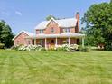 Charming brick home with a metal roof and a welcoming front porch surrounded by lush, well-manicured lawn at 19702 Centennial Rd, Sheridan, IN 46069
