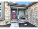 Inviting front porch with stone facade, seating area, and a decorative door at 206 Cranberry Dr, Greenfield, IN 46140