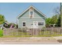 Charming home with light blue siding, white trim, and a fenced yard from across the street at 2230 Pleasant St, Indianapolis, IN 46203
