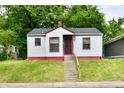 Quaint home with white siding, red trim, concrete steps and iron security door, nestled in greenery at 2966 N Olney St, Indianapolis, IN 46218