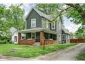 Charming two-story home featuring a welcoming front porch with a porch swing, landscaped yard, and classic architectural details at 31 N Bolton Ave, Indianapolis, IN 46219