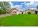 Attractive brick home featuring an attached garage, lush green lawn, and classic American flag displayed at 3537 Woodglen Way, Anderson, IN 46011
