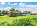 Angle shot of the beautiful brick ranch home showing lush lawn and a mature shade tree at 4197 E 250 S, Franklin, IN 46131