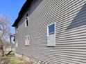 Exterior side view of home with gray siding and boarded windows needing repair at 430 N Hamilton Ave # 430, Indianapolis, IN 46201