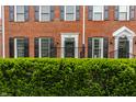 A brick townhome with dark shutters and meticulously trimmed front hedge, offering privacy and charm at 4332 Heyward Pl, Indianapolis, IN 46250