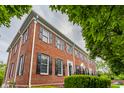 Brick townhouse with black shutters, landscaped bushes and mature trees at 4332 Heyward Pl, Indianapolis, IN 46250