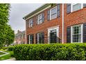 Exterior shot of a red brick townhome with black shutters and manicured landscaping at 4332 Heyward Pl, Indianapolis, IN 46250