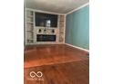 Bright living area featuring a stone fireplace, built-in shelving, and hardwood floors at 5802 Bertha St, Indianapolis, IN 46241