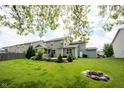 Spacious backyard with lush green lawn, fire pit, landscaping, and a charming pergola-covered patio at 5824 W Commonview Dr, McCordsville, IN 46055