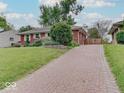 Brick home with a brick paver driveway surrounded by mature trees and landscaping at 6069 E 15Th St, Indianapolis, IN 46219
