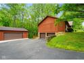 View of the back of the house, featuring multiple garage spaces and mature trees at 6794 E Ann St, Camby, IN 46113