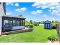Backyard featuring a grill, covered porch, shed and lush green lawn with lake views at 7670 Lippincott Way, Indianapolis, IN 46268