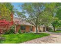 Charming brick home with mature trees, an attached garage, and a well-maintained lawn at 9054 Cinnebar Dr, Indianapolis, IN 46268