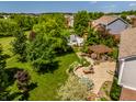 Aerial view of a backyard featuring a patio with pergola, outdoor fireplace, and a swimming pool in a lush yard at 9311 Windrift Way, Zionsville, IN 46077