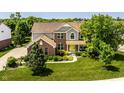 Beautiful two-story home with a well-manicured lawn and colorful landscaping with a bright yellow front door at 9311 Windrift Way, Zionsville, IN 46077