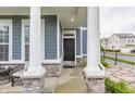 Cozy front porch with stone accents and classic columns, creating an inviting entrance with an outdoor seating area at 965 Astor Ln, Carmel, IN 46032