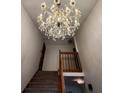 View of the stairs with carpet and wooden banister under an ornate chandelier at 1026 Summer Way Dr, Shelbyville, IN 46176