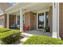 Inviting covered porch featuring chairs, manicured shrubs, brick pillars, and a secure storm door at 10988 Eaton Ct, Fishers, IN 46038