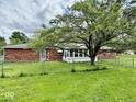 Backyard view of the home showcasing a large tree, fenced yard, and enclosed patio area at 1103 Canal St, Anderson, IN 46012