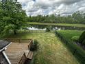 Backyard with a view of a pond with mature trees and a black metal fence at 14462 Brook Meadow Dr, McCordsville, IN 46055