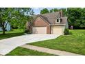 View of the property featuring a two-car garage and a spacious well manicured yard at 14814 Beacon Blvd, Carmel, IN 46032