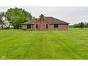 Expansive green backyard featuring a brick home with a chimney and sliding glass doors at 2090 W County Road 400 S, Clayton, IN 46118