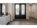 Grand foyer with dark double doors, wood flooring, and a stylish dresser with a mirror, creating an inviting entrance at 4190 Hartswick Ct, Zionsville, IN 46077
