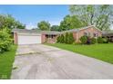 Brick home featuring a long driveway leading to a garage, complemented by a well-maintained lawn at 530 Westmore Dr, Indianapolis, IN 46214