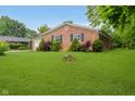 A well-kept lawn surrounds this charming brick home, featuring neatly trimmed shrubs and dark shutters at 530 Westmore Dr, Indianapolis, IN 46214