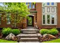 Close-up of the front door entrance featuring stone steps, lush landscaping, and a well-maintained brick facade at 7601 W Stonegate Dr, Zionsville, IN 46077