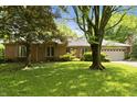 Beautiful brick home with a well-kept lawn and mature trees that provide shade in the front yard at 8909 Ellington Dr, Indianapolis, IN 46234