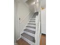 Elegant staircase featuring gray patterned steps, white wood railing, and natural light coming in at 10172 Watkins Ct, Indianapolis, IN 46234