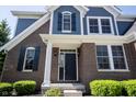 Elegant front entrance featuring a dark front door, classic brickwork, and manicured landscaping at 12600 Misty Ridge Ct, Fishers, IN 46037