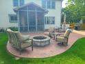 Inviting patio with a stone fire pit, comfortable seating, and a screened-in porch, ideal for outdoor entertaining at 13497 Dunes Dr, Carmel, IN 46032
