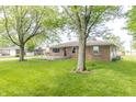 Lush backyard featuring a brick home with a deck and mature trees at 156 N Eastern Village Dr, Greenfield, IN 46140