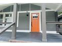 Inviting front porch with gray railings, an orange front door, and stylish lighting fixtures at 1718 Thaddeus St, Indianapolis, IN 46203