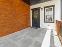 Inviting covered porch with wood accent wall, stylish front door, and concrete floor at 1837 S East St, Indianapolis, IN 46225